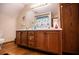 Bathroom featuring double sinks, rustic wooden cabinets, wooden floors, and neutral wall colors at 6980 Lamplighter Ln, Winston, GA 30187