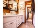Bathroom with double sinks, white cabinets, and a doorway leading to a walk-in closet at 6980 Lamplighter Ln, Winston, GA 30187
