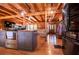 Open kitchen with wooden beams, modern appliances, center island, and views into the living and dining spaces at 6980 Lamplighter Ln, Winston, GA 30187