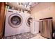 A tidy laundry room with modern washer and dryer units, shelving, and stylish floor mat at 6980 Lamplighter Ln, Winston, GA 30187