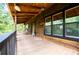 Expansive wooden porch featuring a covered ceiling, black framed windows, and outdoor seating with forest views at 6980 Lamplighter Ln, Winston, GA 30187