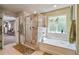 Bright bathroom featuring a glass shower, soaking tub, and large window with backyard views at 317 Basel Way, Hampton, GA 30228