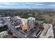 View of a brick high rise building with a green roof surrounded by streets and full parking lots and wooded areas at 3820 Roswell Ne Rd # 705, Atlanta, GA 30342