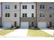 A row of newly constructed townhomes each featuring individual one-car garages and unique brick designs at 4962 Villager Ln, Stone Mountain, GA 30083