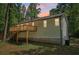 Back exterior of house showing wooden deck and stairs leading down to yard at 7160 Royston Way, Cumming, GA 30028