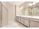 Bathroom featuring a double vanity with cabinets, modern lighting, and a tiled shower with glass doors at 305 Duval Dr, Alpharetta, GA 30009