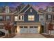 Exterior of a two-story townhouse with a two-car garage and blue and brick accents at dusk at 305 Duval Dr, Alpharetta, GA 30009