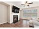 Cozy living room with a fireplace, ceiling fan, hardwood floors, and large windows at 305 Duval Dr, Alpharetta, GA 30009