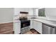 Clean kitchen features stainless steel appliances, double sink, white cabinets, and wood-look flooring at 563 Navarre Dr, Stone Mountain, GA 30087