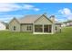 Home's back exterior highlighting a spacious yard and covered patio with stone fireplace at 100 Nemoura Ct, Fairburn, GA 30213