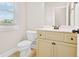 Well-lit bathroom featuring a cream-colored vanity, mirror, and window, with a toilet on the side at 100 Nemoura Ct, Fairburn, GA 30213