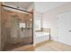 Luxurious bathroom featuring a walk-in shower with glass door and a separate soaking tub for a spa-like experience at 100 Nemoura Ct, Fairburn, GA 30213