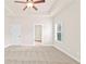Spacious bedroom features neutral carpeting, tray ceiling with ceiling fan, and ample natural light from the large window at 100 Nemoura Ct, Fairburn, GA 30213