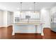 This kitchen features white cabinets, a large center island, pendant lights, stainless appliances, and hardwood floors at 100 Nemoura Ct, Fairburn, GA 30213