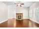 Open-concept living room with hardwood floors, fireplace, and bright natural light from shuttered windows at 100 Nemoura Ct, Fairburn, GA 30213