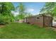 A view of the spacious backyard surrounded by lush greenery, and a classic brick house at 2015 Twelve Oaks Nw Cir, Kennesaw, GA 30144