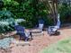 A cozy stone fire pit with Adirondack chairs arranged around the perimeter at 10635 Sugar Crest Ave, Johns Creek, GA 30097