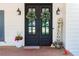 Elegant black double front doors adorned with wreaths and surrounded by decorative accents and plants at 10635 Sugar Crest Ave, Johns Creek, GA 30097