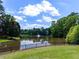 Scenic view of a pond with a fountain, surrounded by lush greenery and trees at 10635 Sugar Crest Ave, Johns Creek, GA 30097