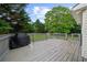 Wooden deck with gray railings and a grill overlooking the back yard with mature trees and lawn at 7020 Walnut Mill Lndg, Cumming, GA 30040