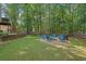 Backyard fire pit with Adirondack chairs surrounded by a wooded area, perfect for relaxing outdoors at 4410 Red Rock Pt, Suwanee, GA 30024
