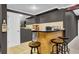 Basement bar area with wood cabinets, granite countertops, mini fridge, and seating for entertaining at 4410 Red Rock Pt, Suwanee, GA 30024