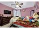 Cozy bedroom featuring pink walls, ceiling fan and a window bringing in natural light at 4410 Red Rock Pt, Suwanee, GA 30024