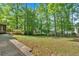 A wide backyard with green grass, mature trees, and concrete patio section at 4181 Singing Post Ne Ln, Roswell, GA 30075