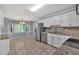 Well-lit kitchen with white cabinetry, stainless steel appliances, tile flooring, and an adjacent breakfast nook at 4181 Singing Post Ne Ln, Roswell, GA 30075