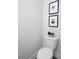 Neat half bath featuring decorative wall hangings, white toilet and grey walls at 4966 Villager Ln, Stone Mountain, GA 30083