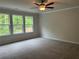 Bedroom featuring three large windows with wooded views, carpeted floor, and modern ceiling fan at 93 Riverwood Dr, Dallas, GA 30157