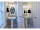 Bright bathroom featuring double pedestal sinks, oval mirrors, and a sleek storage tower at 1390 Almont Sw Dr, Atlanta, GA 30310
