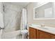 Bathroom featuring a shower with white marble style tiles, a white vanity with a wood cabinet, and a decorative mirror at 5022 Audubon Pl, Norcross, GA 30093