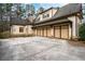 Side view of a three-car garage with attached home featuring stone accents and manicured landscaping at 6213 Arnall Nw Ct, Acworth, GA 30101