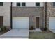 Charming townhome exterior features a one-car garage, a brown door, and well-maintained landscaping at 4970 Villager Ln, Stone Mountain, GA 30083