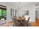 Dining area adjacent to a screened-in porch, features a modern chandelier and hardwood floors at 4876 Sara Creek Way, Sugar Hill, GA 30518
