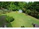Aerial view of a large grassy backyard with mature trees and a storage shed at 30 W Fork Way, Temple, GA 30179