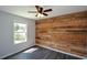 Bedroom featuring a wood accent wall, window, and ceiling fan at 30 W Fork Way, Temple, GA 30179