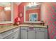 Whimsical bathroom with vibrant pink wallpaper, granite countertop, and white cabinetry at 4823 Layfield Dr, Dunwoody, GA 30338