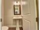 Cozy powder room featuring a pedestal sink, decorative mirror, and neutral color palette at 520 Pearl St, Cumming, GA 30040