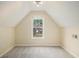 An inviting carpeted room under a sloped ceiling with a window view of a charming house at 602 Jules Crest Ct, Lawrenceville, GA 30045