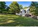 View of the home's backyard with sloped lawn, a deck with stairs, chimney, and many mature trees at 1875 Bernice Dr, Cumming, GA 30041