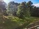 Backyard view showcasing the lawn and wooden staircase leading to a deck surrounded by mature trees at 1875 Bernice Dr, Cumming, GA 30041