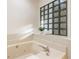 Bright bathroom featuring a soaking tub with glass block window and tile surround at 1875 Bernice Dr, Cumming, GA 30041
