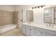 Bright bathroom features double sinks, large mirrors, updated fixtures, and a tiled shower and tub at 1875 Bernice Dr, Cumming, GA 30041
