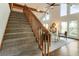 Carpeted staircase featuring natural wood railing ascending into living room with windows and exposed beams at 1875 Bernice Dr, Cumming, GA 30041
