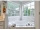 Bright bathroom featuring a large tub with tile surround and windows at 3060 Baymount Dr, Lawrenceville, GA 30043