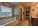 A luxurious bathroom with large soaking tub and window, tiled floors and a walk-in closet at 1185 Gallatin Way, Suwanee, GA 30024
