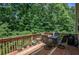 Wooden deck with a table, chairs, grill, and a view of a lush green forest at 1185 Gallatin Way, Suwanee, GA 30024