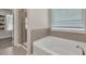 Neutral bathroom featuring a soaking tub beneath a window and glass-enclosed shower at 211 Aspen Valley Ln, Dallas, GA 30157